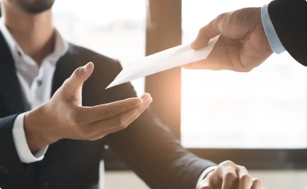 closeup of someone handing an envelope to someone else